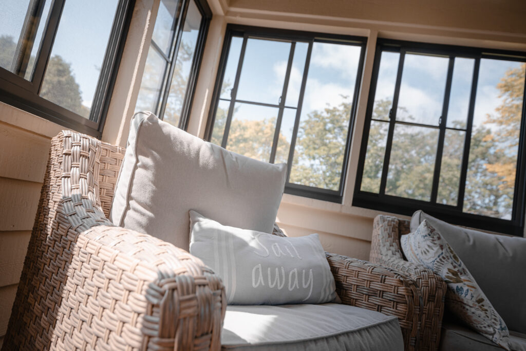 An enclosed porch with white sofas under a vaulted ceiling
