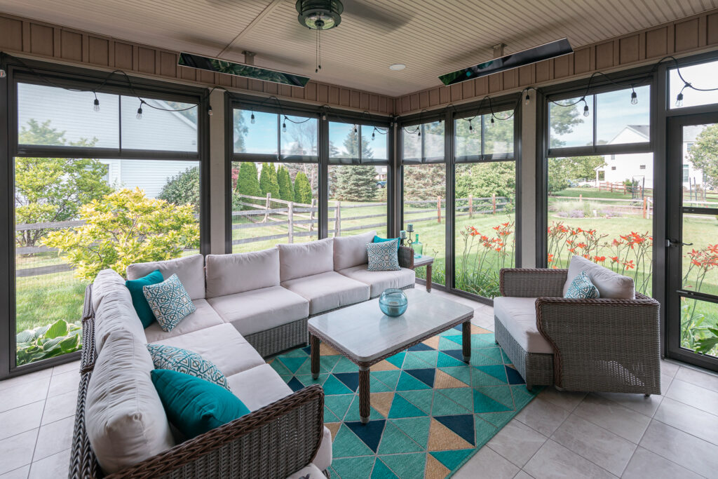 A bright sunroom with a sectional sofa and garden views