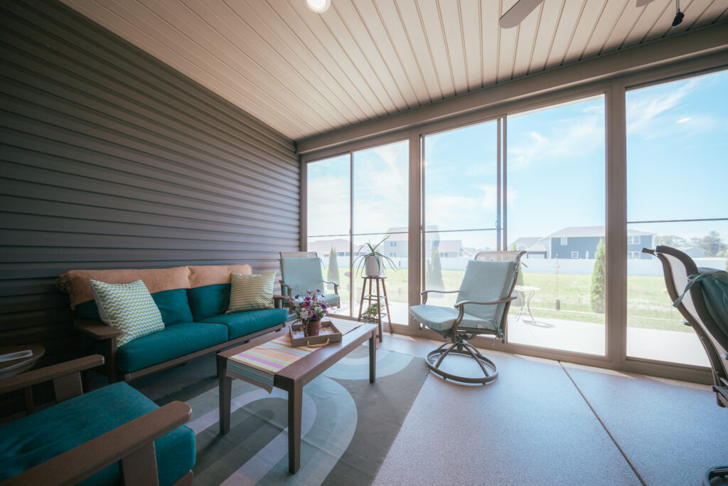 A sunroom with a teal sofa and views of the lawn