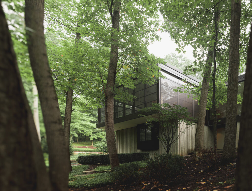 A porch enclosure with dark frames surrounded by trees