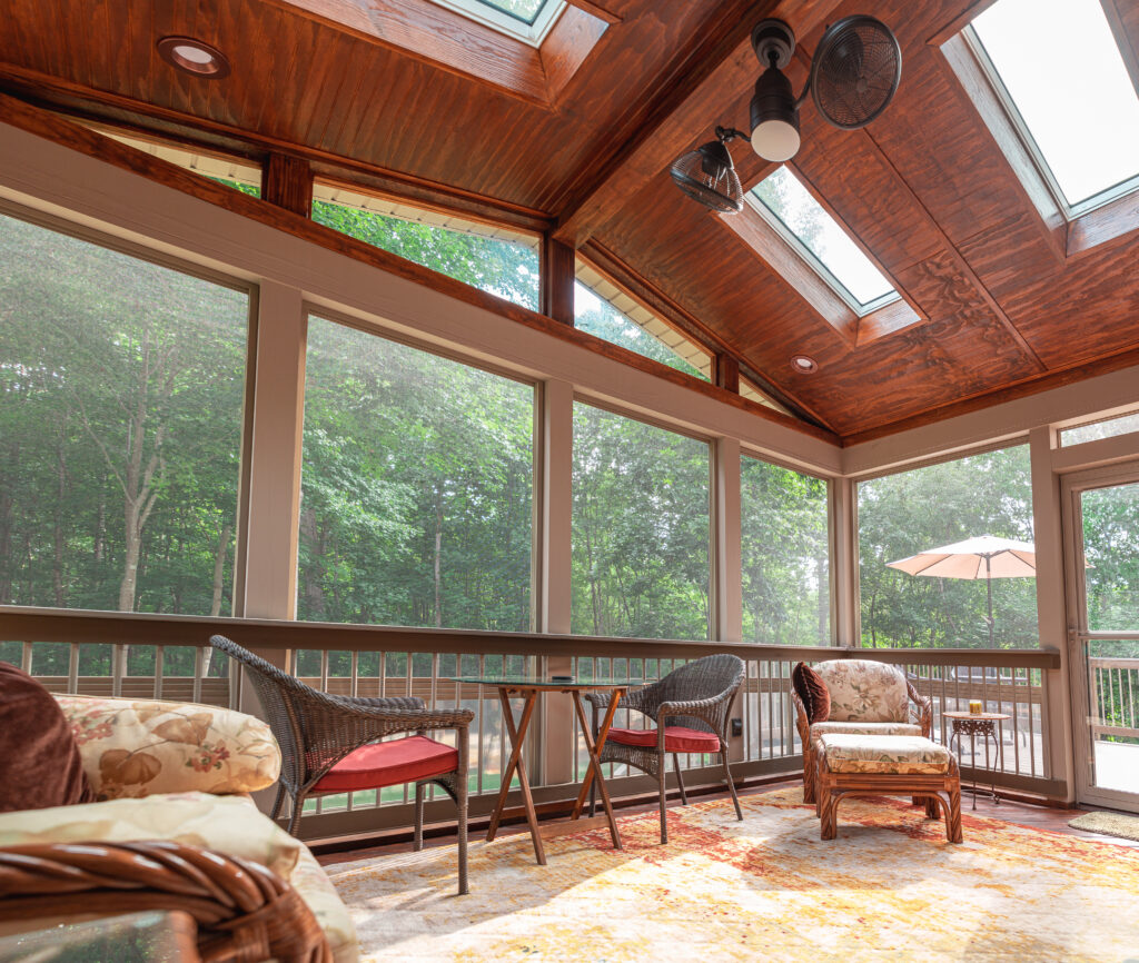 An enclosed porch with a wood ceiling looking out to the woods